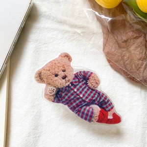 Detail of cute teddy bear acrylic phone grip with a 3D effect on a white textured surface