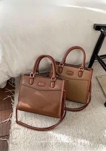 Détail de deux sacs cabas en cuir marron et caramel posés sur un tapis en cachemire beige