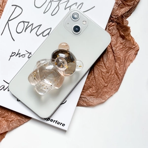 Macro detail of bear-shaped phone grip with gold foil flakes on a green smartphone