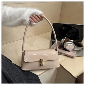 Détail d'un sac baguette en cuir verni beige brillant avec une boucle en métal doré