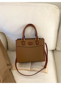 Sac cabas vintage en patchwork caramel posé sur des livres sur un canapé blanc chic