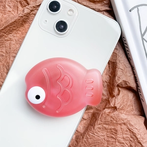 Close-up of a pink fish-shaped phone grip attached to a white smartphone back