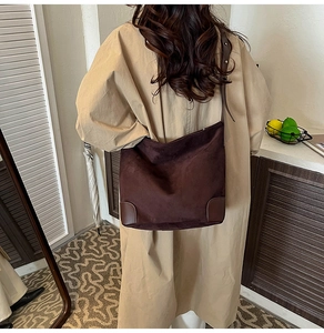 Detail of dark brown suede tote bag with reinforced leather corners and adjustable strap