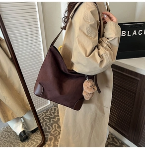 Detail of dark brown suede tote bag with leather straps and plush bear charm