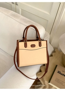 Détail esthétique rétro de la bandoulière contrastée beige et marron d'un cabas