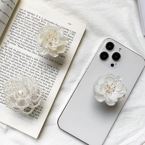 Detail of 3D rose flower and pearl phone socket grip on a vintage book backdrop