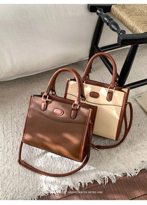 Détail de deux sacs cabas rétro en marron et beige contrasté sur un lit blanc