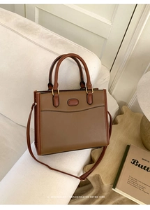 Gros plan du sac vintage en similicuir marron avec détails dorés sur canapé
