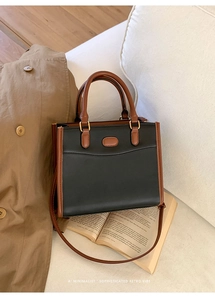 Détail du sac fourre-tout rétro bicolore sur un livre avec cuir noir et anses marron
