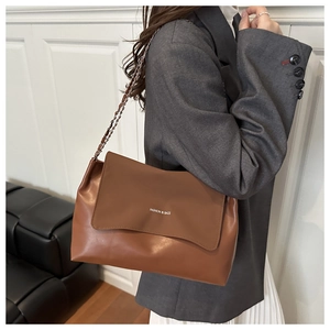Brown leather tote bag featuring metal chain strap and minimalist fashion lettering detail