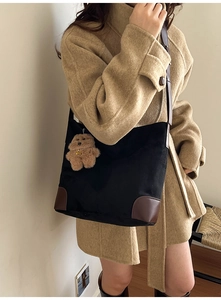 Close-up of black canvas tote bag with leather corner patches and cute bear charm