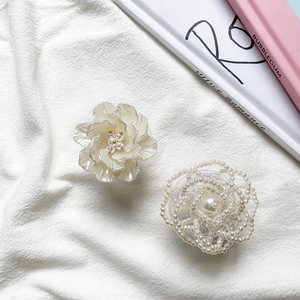 Close-up of elegant cream rose and pearl petal phone grip on a white textured fabric