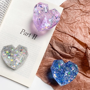 Macro view of geometric heart phone grips with sparkling sequins on vintage book background