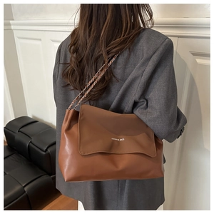 Detail of brown leather tote bag with metal chain strap and 'FASHION & BAGS' engraving
