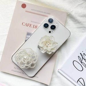 Detail view of pearl-woven flower and resin rose phone grip on a white smartphone