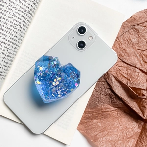 Detail of blue heart-shaped epoxy phone grip with glitter and sequins on a smartphone