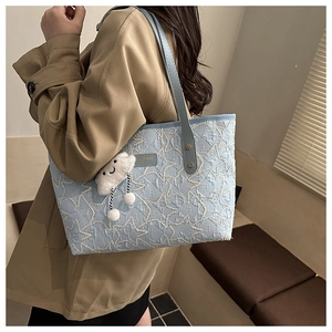 Detail of light blue quilted tote bag with star patterns and plush cloud pendant
