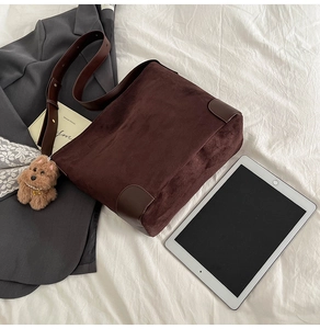 Close-up of large brown suede tote bag with leather trim and a cute puppy charm