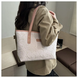 Detail view of large quilted tote bag with pink leather straps and woven texture