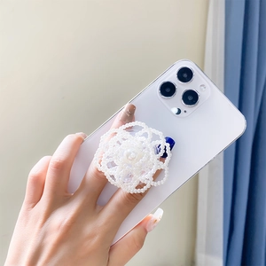 Detailed view of an elegant white pearl rose flower phone socket grip on a smartphone
