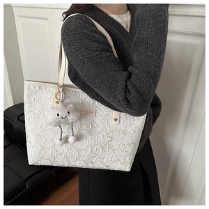 Detailed texture of off-white floral tote bag with a cute cloud plush charm