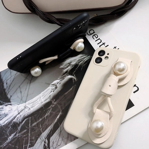 Detail view of pearl wrist strap on matte silicone phone case for iPhone 16 series