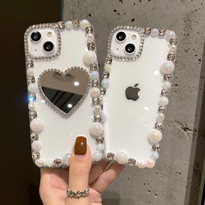 Close-up of clear iPhone case featuring luxury pearl accents and a heart mirror detail