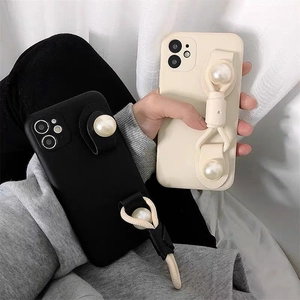 Detail of elegant pearl wristband phone cases in black and cream for iPhone