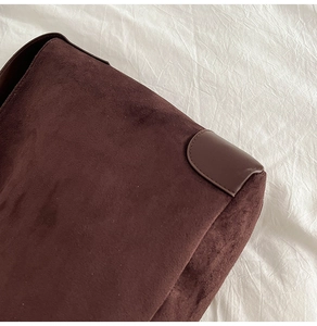 Detailed macro view of deep brown suede texture and reinforced leather stitching on tote bag