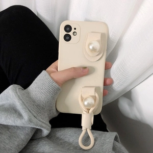 Detail of cream iPhone case with large pearl ornaments and woven wrist strap for easy grip