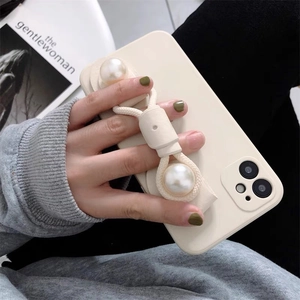 Detail of white iPhone case with pearl wrist strap and woven rope stand decoration