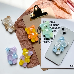 Detailed flat lay of six bear-shaped phone grips with gold foil glitter in assorted colors
