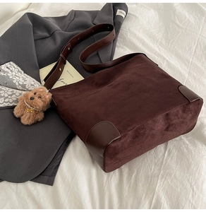 Detailed view of dark brown suede bucket bag with leather base and plush dog charm