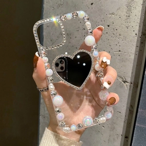 Detail of luxury iPhone case with pearls, rhinestones and heart-shaped makeup mirror