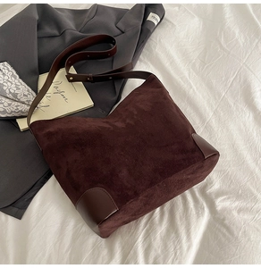 Detail of large brown suede tote bag with leather reinforced corners and shoulder strap