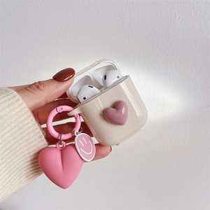 Detail showing creamy white silicone AirPods case with 3D pink heart and matching charm