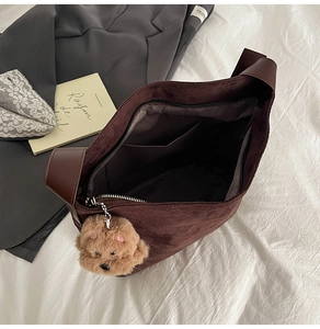 Detailed interior of a brown suede tote bag with zipper closure and bear charm accessory