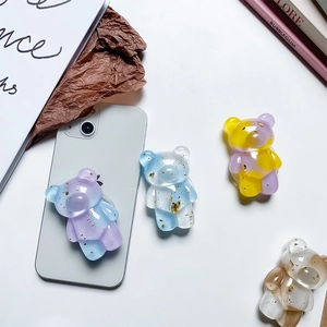 Macro shot of bear-shaped phone grip with gold foil sequins and gradient resin finish
