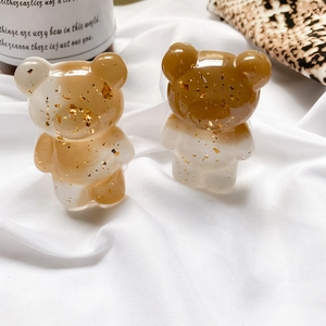 Detail of bear phone grips with gold foil flakes on a textured fabric surface