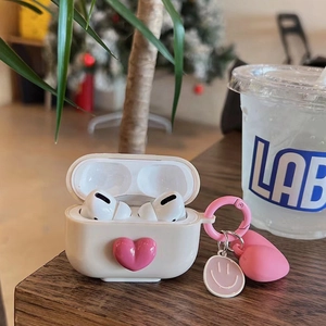 Detail of cream AirPods Pro case with pink 3D heart, metal carabiner, and cute charms