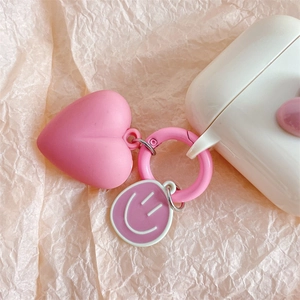 Detail of pink heart and purple smiley face pendant on a white silicone earphone case