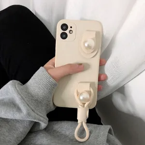 Beige iPhone case with large pearl accents and a matching braided hand strap handle