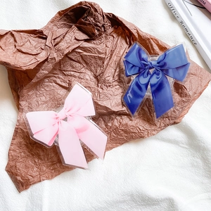 Détail d'accessoires de nœuds rose et bleu royal dans un support de téléphone en acrylique