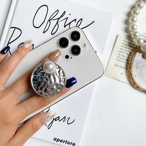 Macro shot of silver hammer-textured phone grip with a large pearl inlay on a smartphone