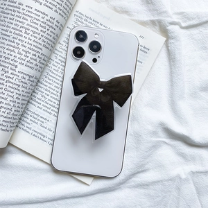 Détail d'un support de téléphone en forme de nœud noir sur un smartphone blanc