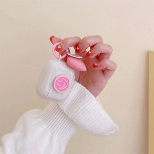 White silicone case for AirPods featuring a pink smiley face relief and heart-shaped charm
