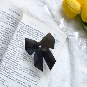Vue détaillée d'un support de téléphone nœud noir sur un livre et des tulipes