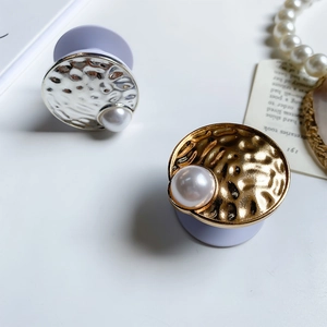 Close-up of hammered metal phone grip with pearl detail in gold and silver finishes