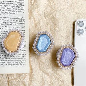 Three gem-shaped phone sockets with pearls and rhinestones on a textured background