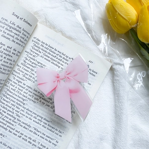 Détail du support téléphone nœud rose sur un livre avec des tulipes et lumière douce
